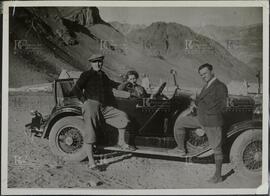 Perón junto a una mujer y un hombre posando en un auto